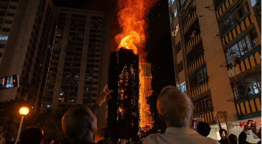 La gente observa las llamas que envuelven un edificio del distrito de Tai Po, en el norte de Hong Kong, el 26 de noviembre de 2025. Chan Long Hei / AP
