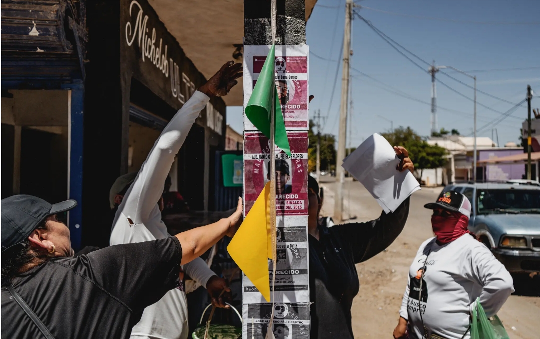 Miembros de un colectivo de búsqueda pegando volantes con fotos de personas desaparecidas en Corerepe.