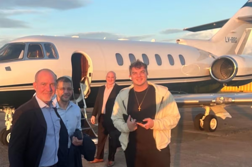 Hayden Davis, de campera color crema, antes de subir a un jet durante su visita a la Argentina